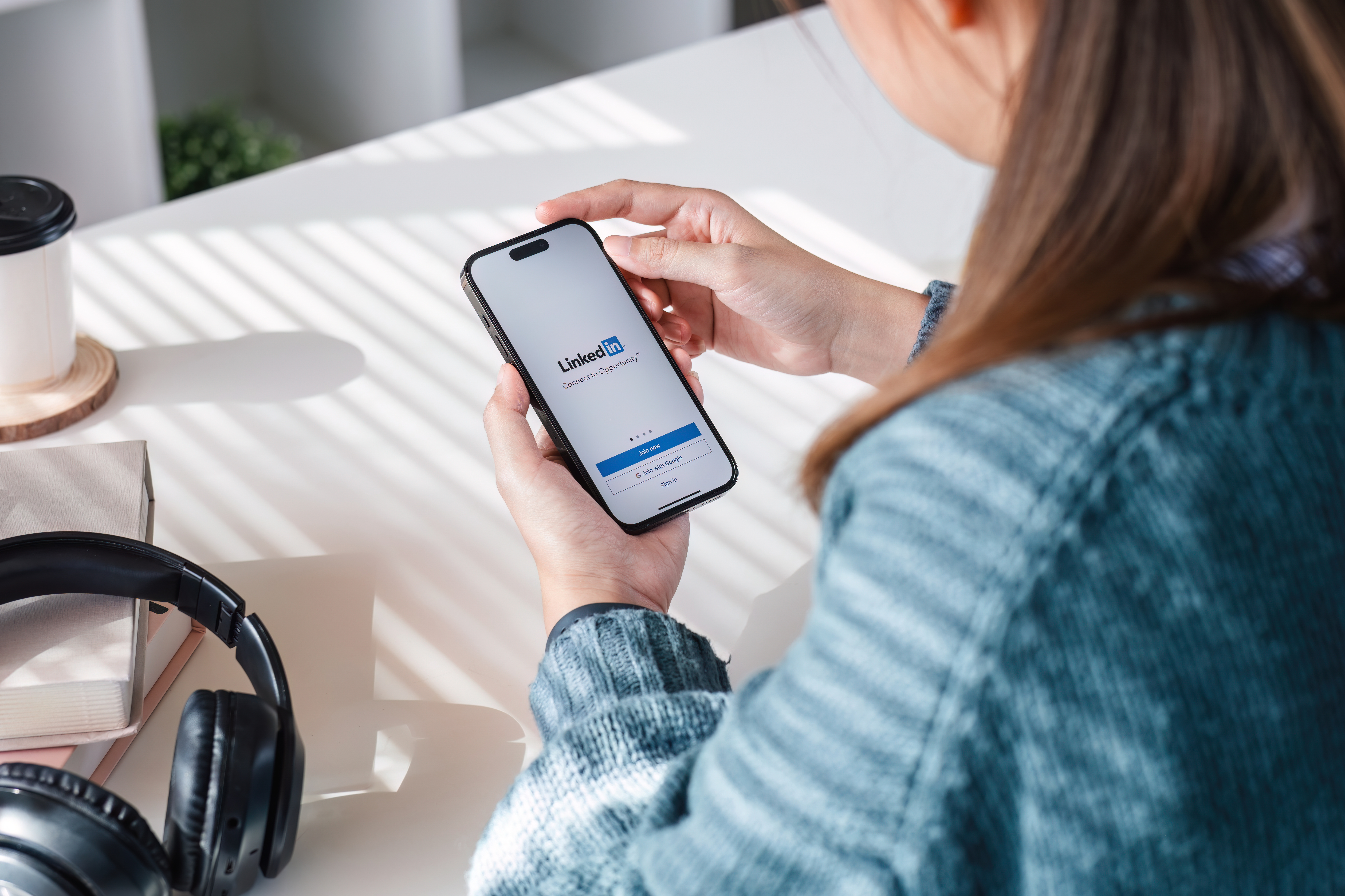 Person hält Smartphone mit geöffneter LinkedIn-Anmeldeseite.